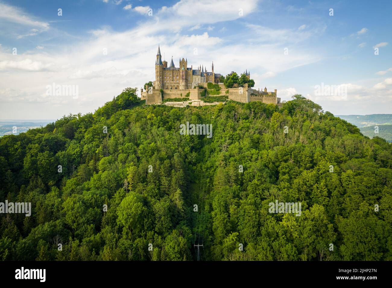 Drone shot of Hohenzollern Castle on forested mountain top in the ...