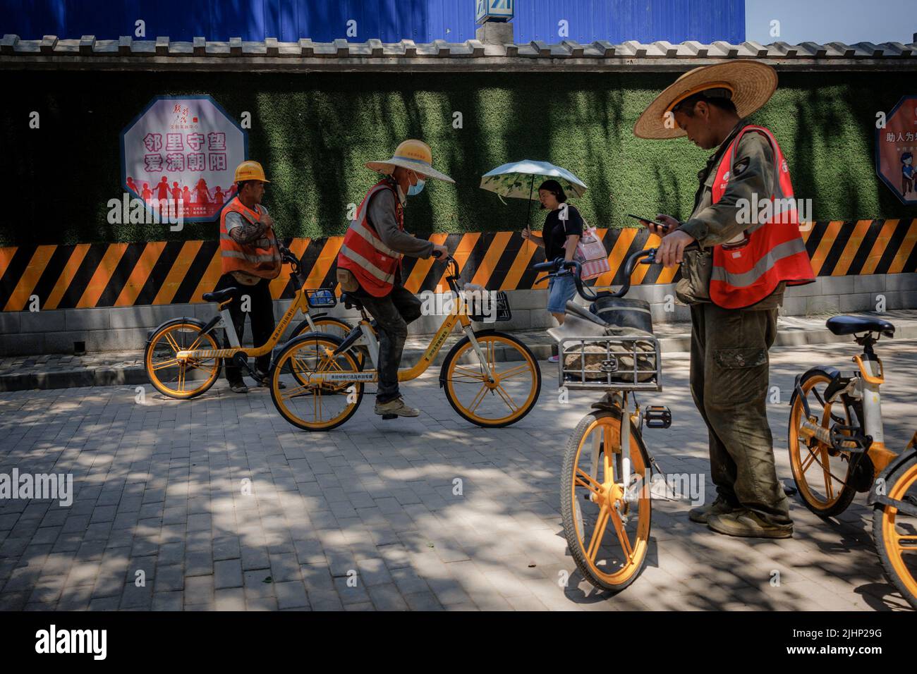Workers use shared bicycles outside a construction site in Beijing, China, July 20, 2022. REUTERS/Thomas Peter Stock Photo