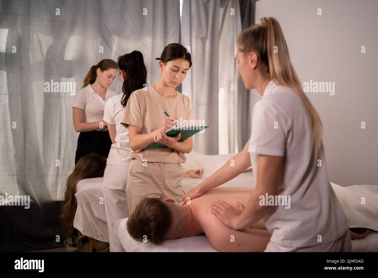 Teacher helping student training to become masseuse, women doing back massage to patient, wellness massage training concept Stock Photo