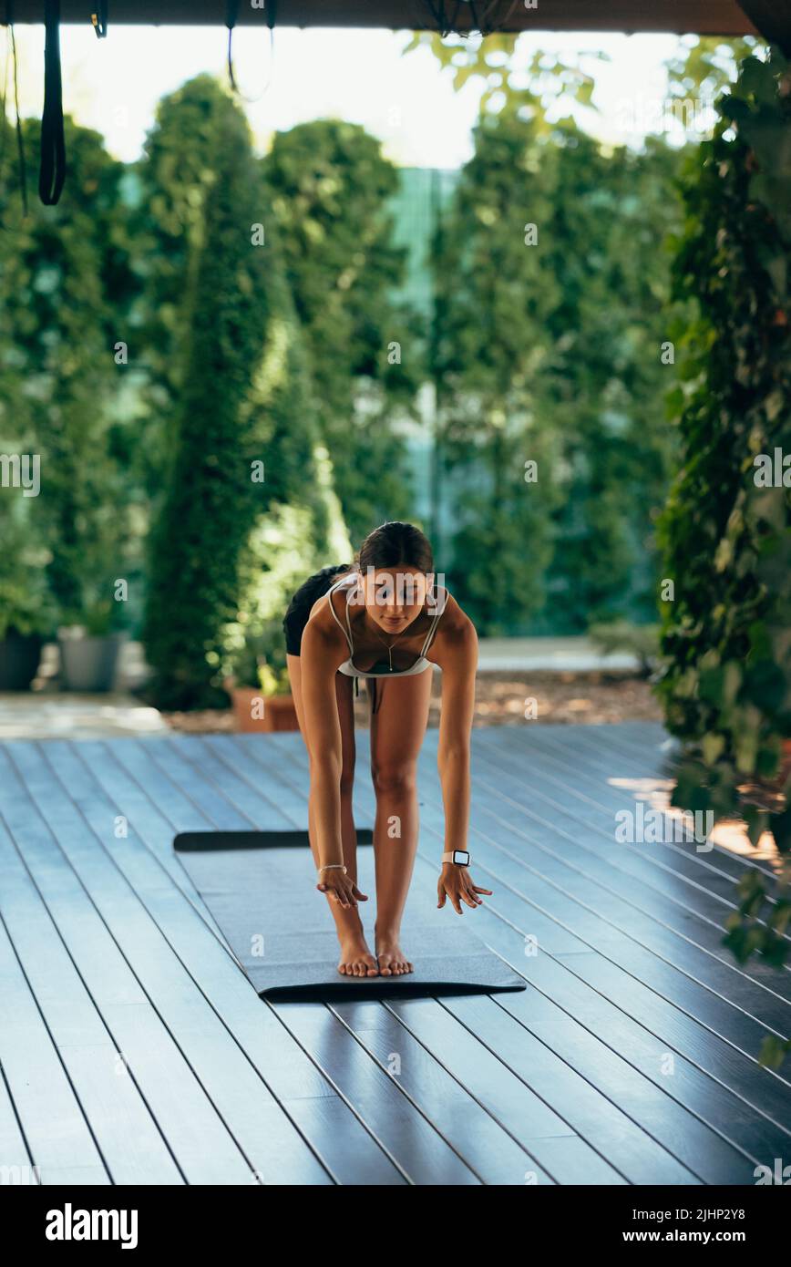 Young woman performs uttanasana. Practicing yoga alone Stock Photo