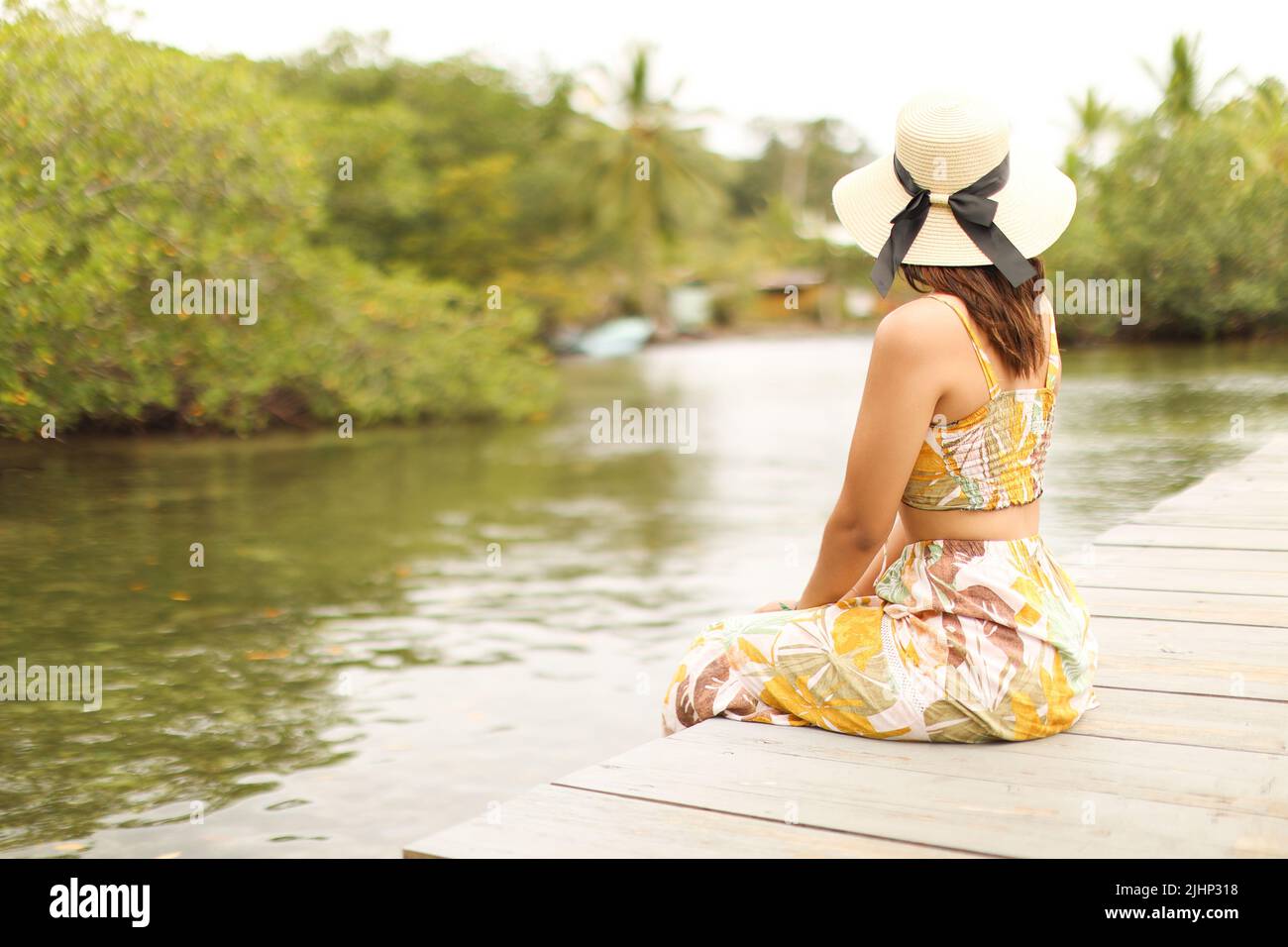 Young woman looking sitting in dock with hat and dress at bocas del toro panama Stock Photo