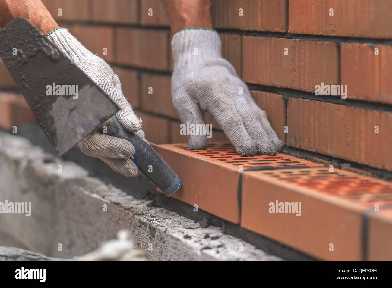 Mason trowels smears cement mortar on brick. Bricklaying when building house or stone fence. Stock Photo