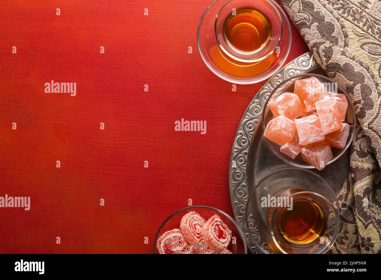 Tea in traditional glass cups  and  turkish delight  on red painted wooden background  with empty space for text . Flat lay. Selective focus Stock Photo