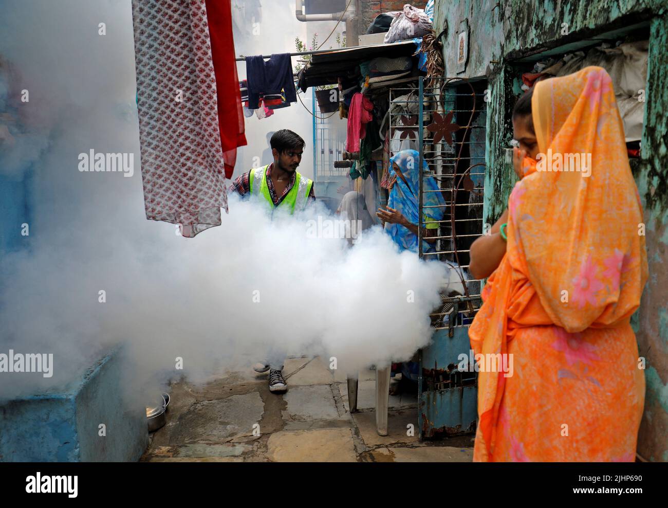 Women cover their faces as a health worker fumigates a residential neighbourhood during a drive to prevent the spread of mosquito-borne diseases following recent rainfall and water logging, in Ahmedabad, India, July 20, 2022. REUTERS/Amit Dave     TPX IMAGES OF THE DAY Stock Photo