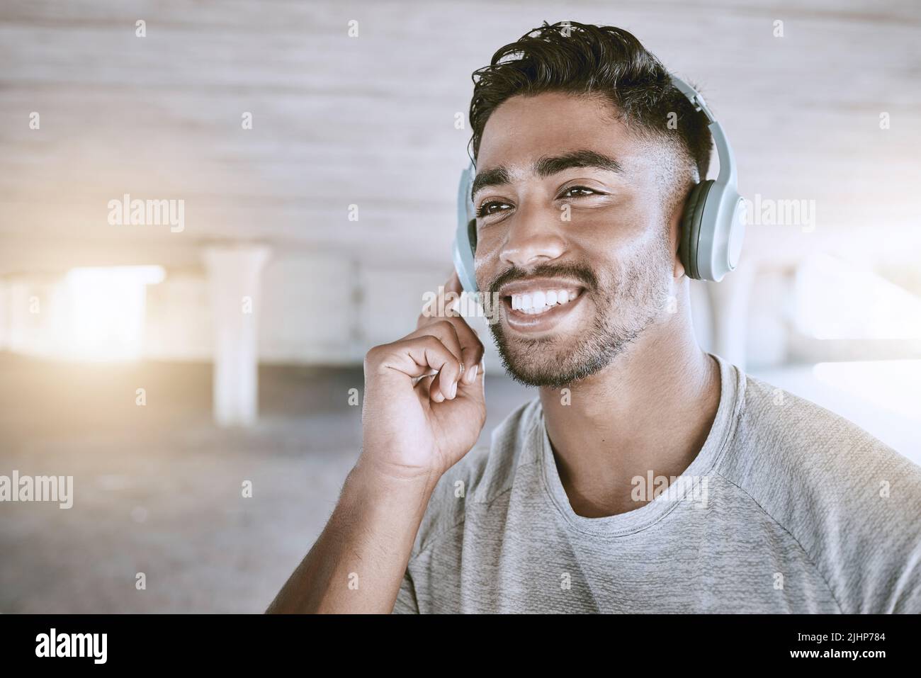 Fit young man listening to music through headphones while exercising outdoors. Taking a break from his workout and run Stock Photo