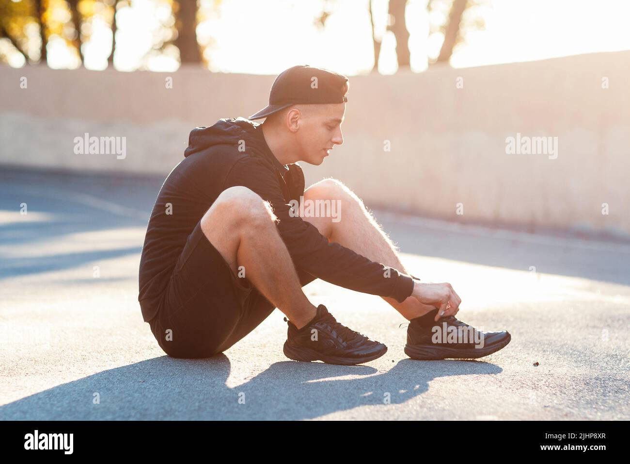 Young sporty man sitting on ground at stadium Stock Photo - Alamy