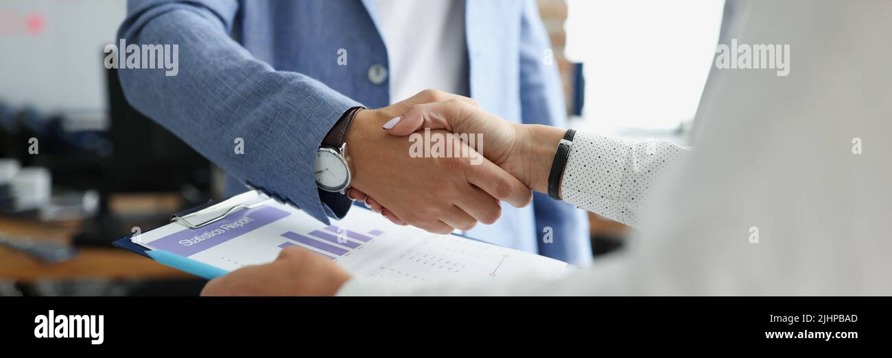 Partners shake hands over business statistics report paper Stock Photo