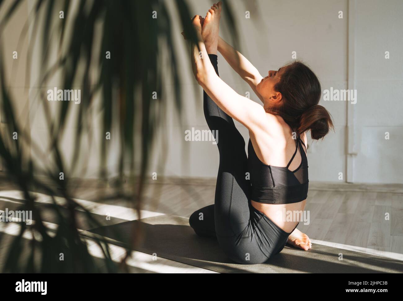 Young fit woman practice yoga doing asana in light yoga studio