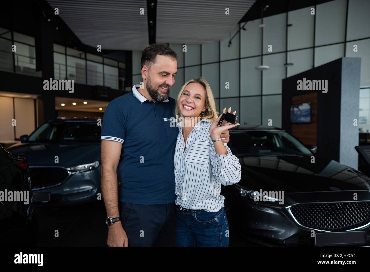 Happy caucasian couple hugging and woman holding new car keys in car ...
