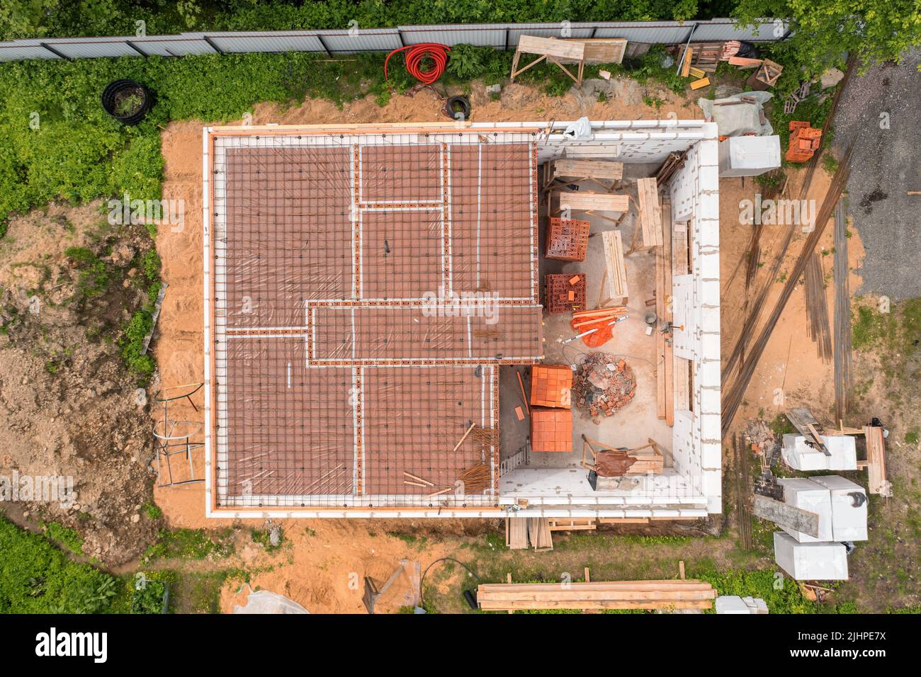 Country house under construction with building materials, tools and garbage. Directly above aerial view Stock Photo