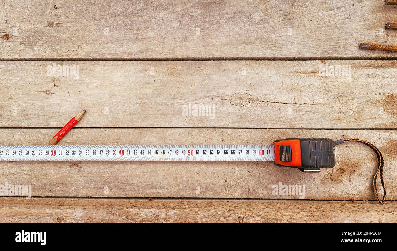 Tape measure and pencil on a wooden workbench. Textured wooden table with tools and copy space on the table Stock Photo