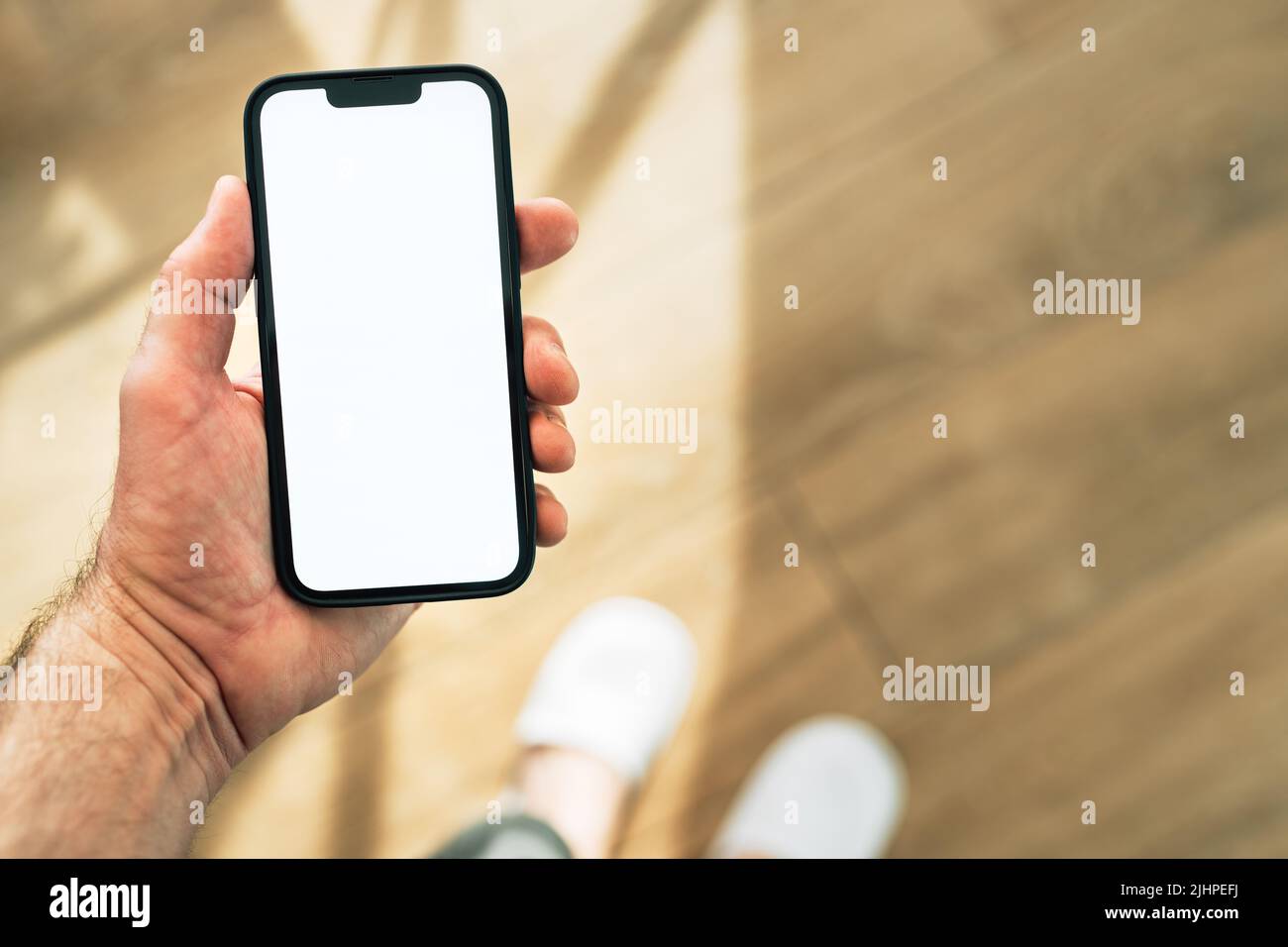 Smartphone mockup, internet of things and smart home concept, man using mobile phone. Close up of hand holding device with blank screen in home interi Stock Photo