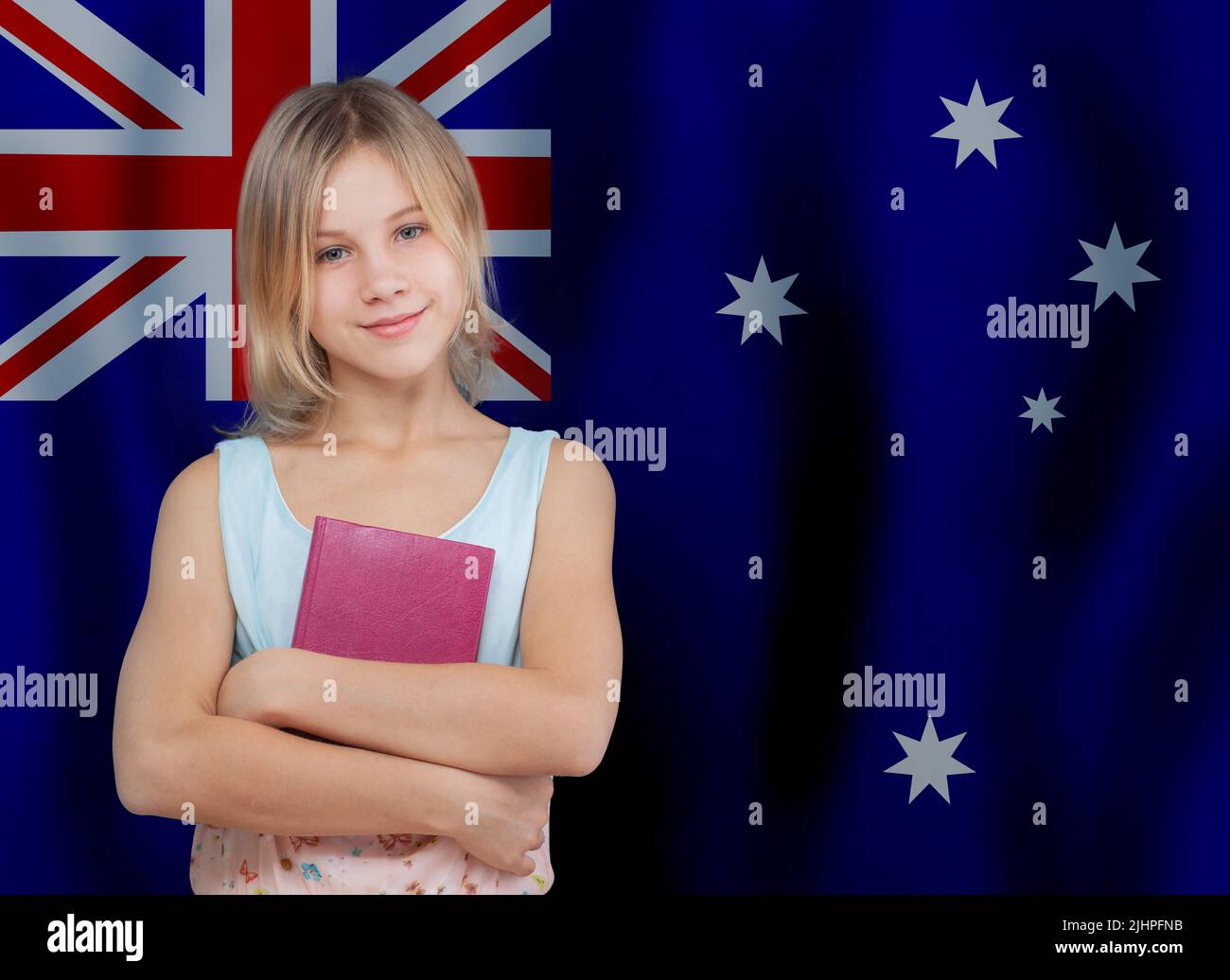 School student girl standing with book on Australian flag background. Education and school in Australia concept. Stock Photo