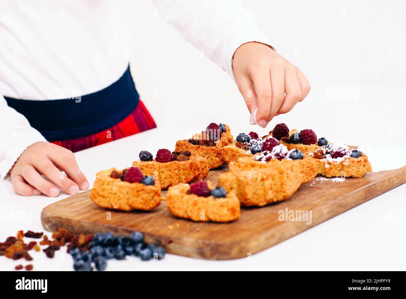 Girl decorating berry cakes with sugar powder Stock Photo