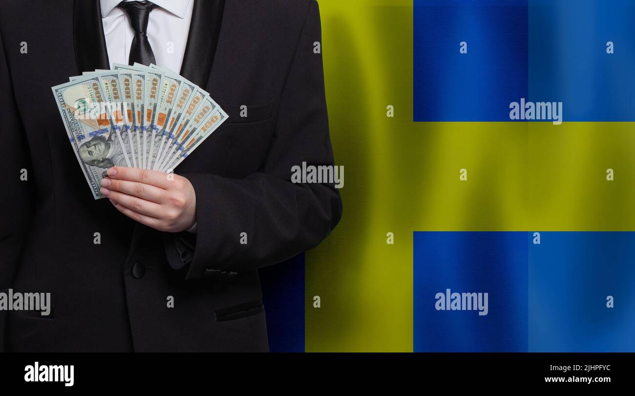 Hand with 100 US dollar bills money banknotes against flag of Sweden