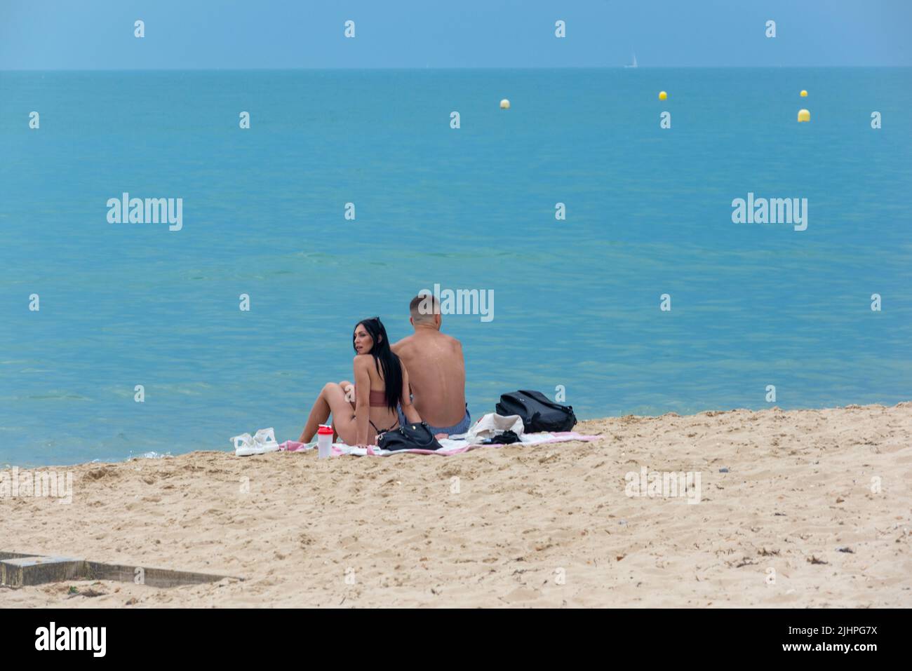Boscombe, Bournemouth, Dorset, England, UK, 19th July 2022, Weather. Couple sitting on beach looking out to see with dark sky at end of heatwave. Stock Photo