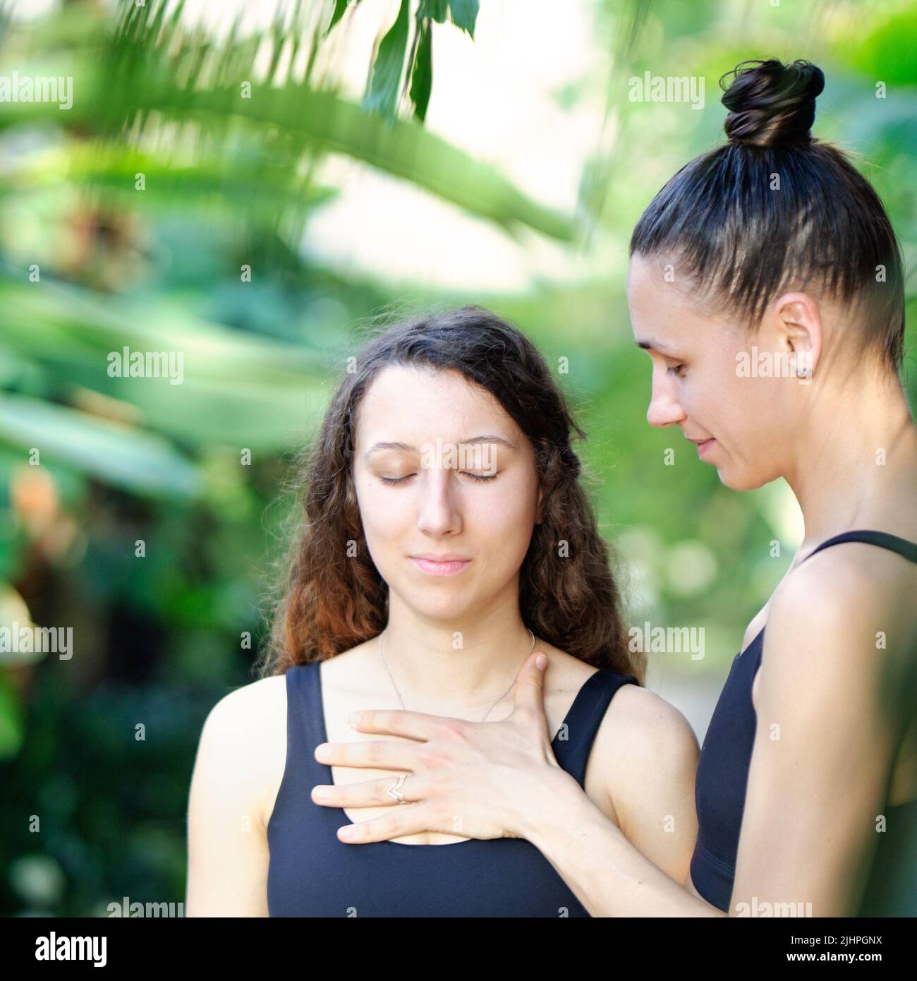 Yoga concept, meditation and sound therapy. Beautiful young girl at yoga session with her yoga and meditation teacher at tropical yoga retrear Stock Photo