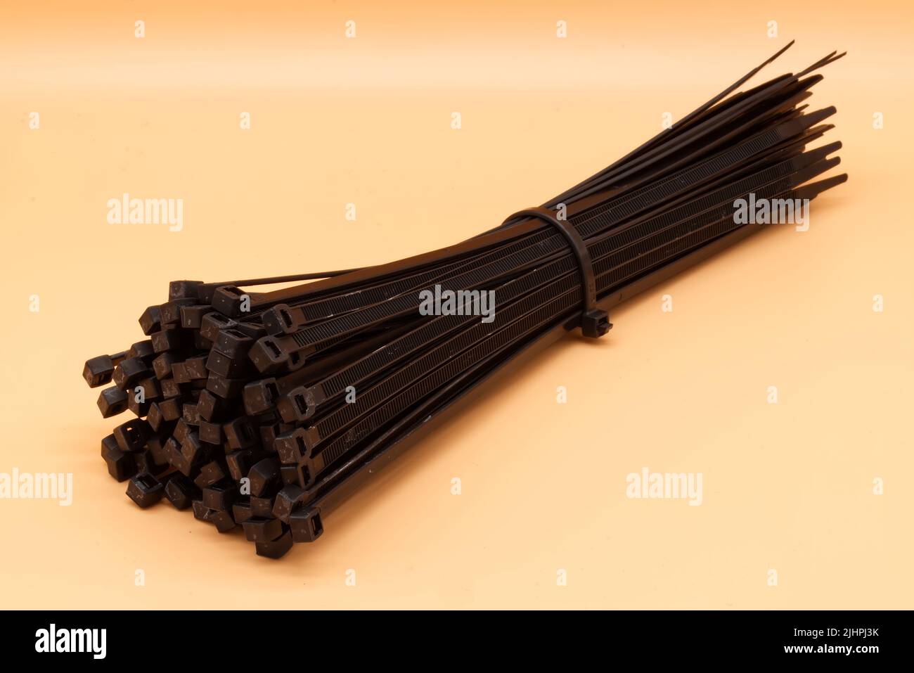 Black cable ties isolated on orange background. Plastic Tie Wraps. Stock Photo
