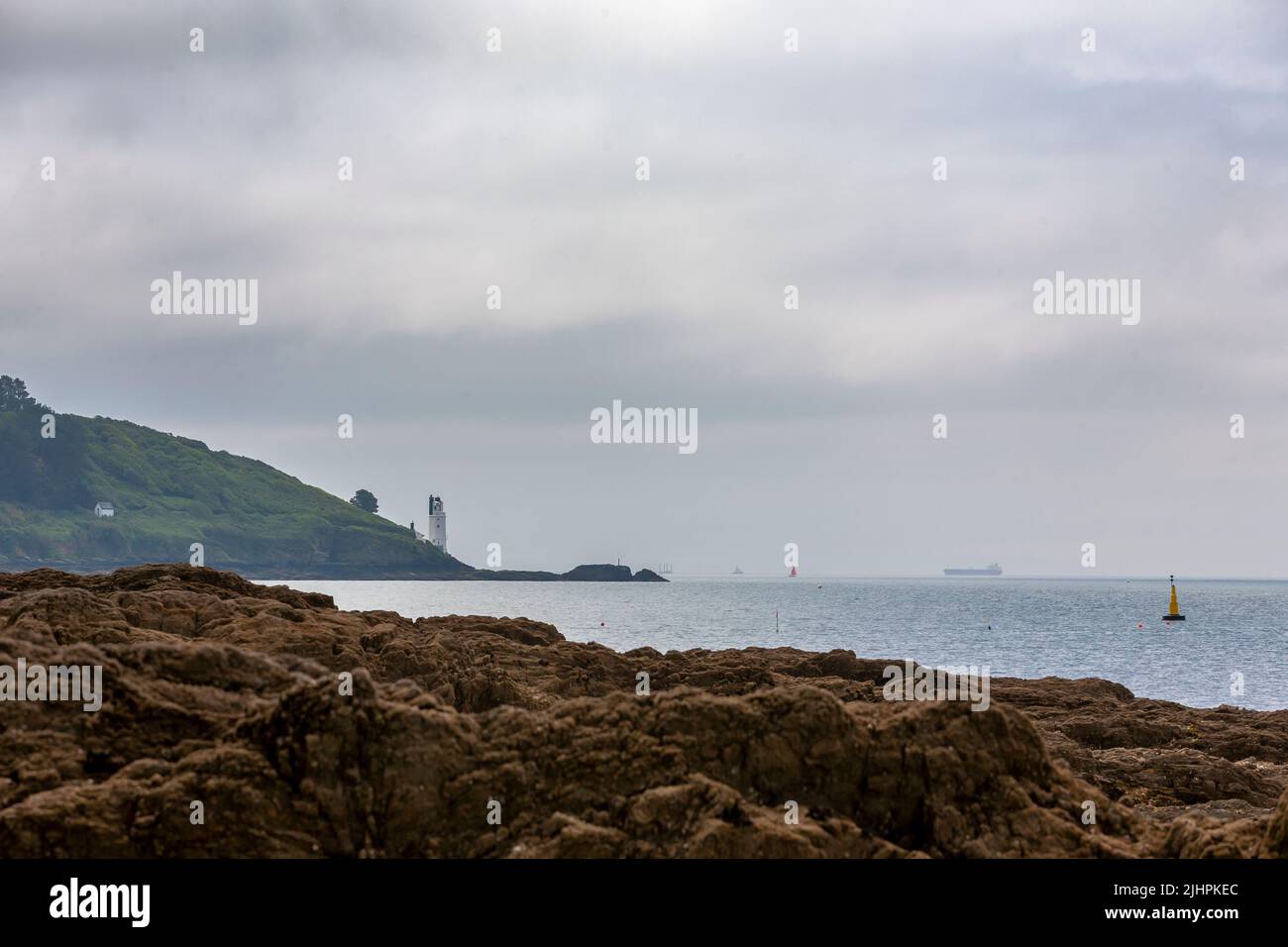 Mouth of the River Fal, with the lighthouse on St. Anthony Head across the entrance to the Percuil River, from Castle Cove, St. Mawes, Cornwall, UK Stock Photo