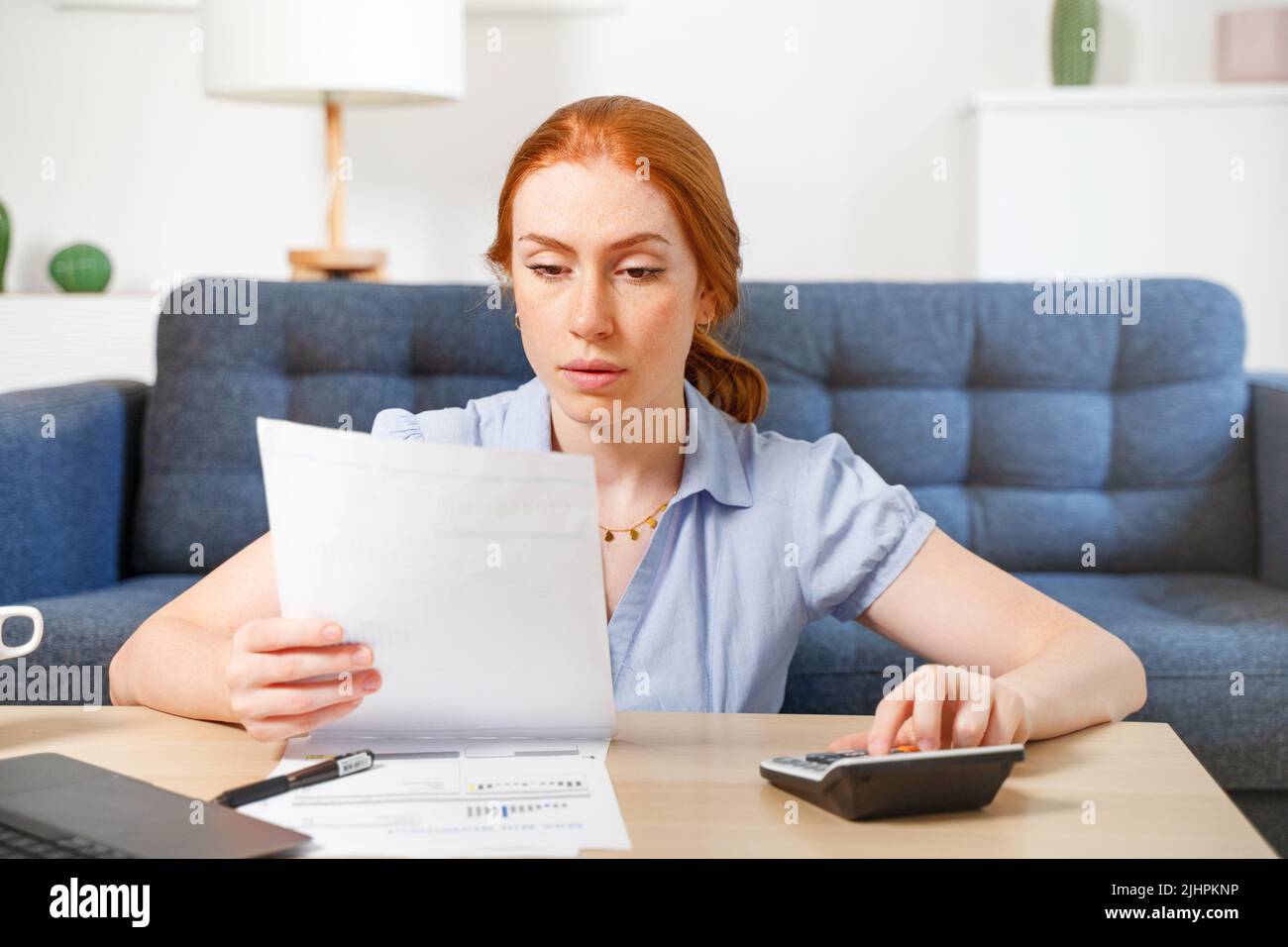 One woman examining documents and using laptop while working at home Stock Photo