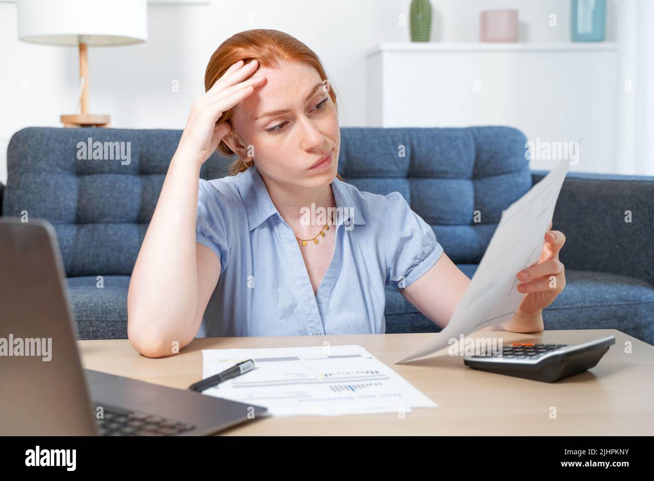 One woman examining documents and using laptop while working at home Stock Photo
