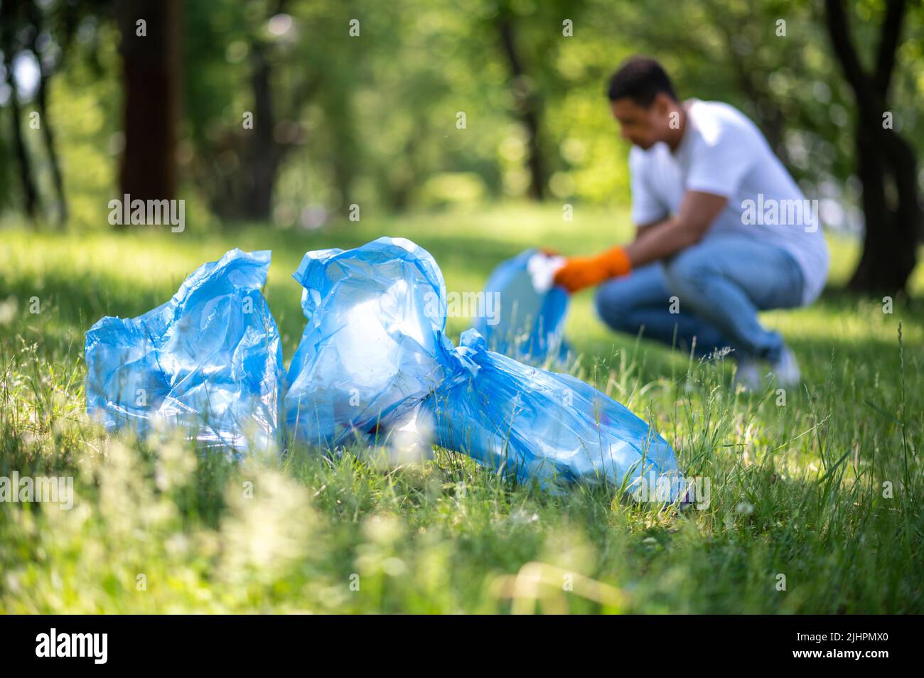 Garbage bags and man behind picking up trash Stock Photo Alamy