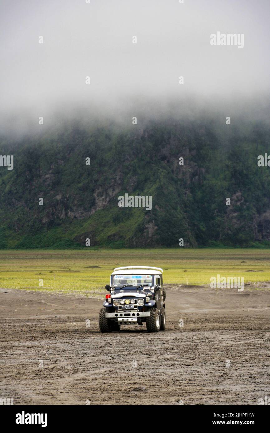 Japanese classic jeep FJ40 for tourist transportation parking alone at Mount Bromo in the Tengger Semeru National Park. No people. Fog above the jeep. Stock Photo