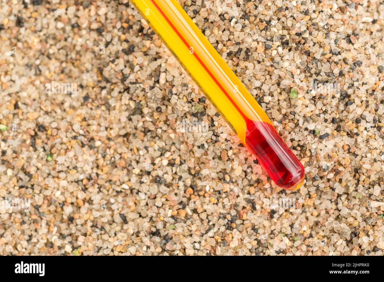Glass red ink thermometer bulb on coarse sand background. For 2022 Summer heatwave, UK heatwave, hot weather, high temperatures, red hot, severe heat. Stock Photo