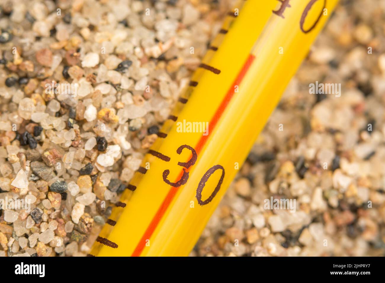 Close-up glass alcohol thermometer on coarse sand, reading 36 C. For 2022 Summer heatwave, UK heatwave, hot weather, high temperatures, severe heat Stock Photo