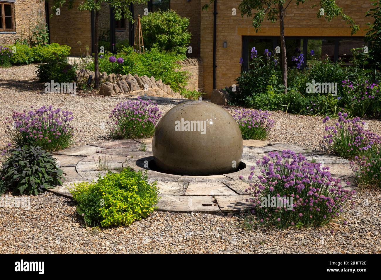 Round circular herb garden with stone ball water feature in english garden Stock Photo
