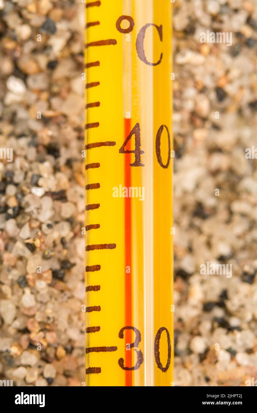 Close-up glass alcohol thermometer on coarse sand, reading 40 C. For 2022 Summer heatwave, UK heatwave, hot weather, high temperatures, severe heat Stock Photo