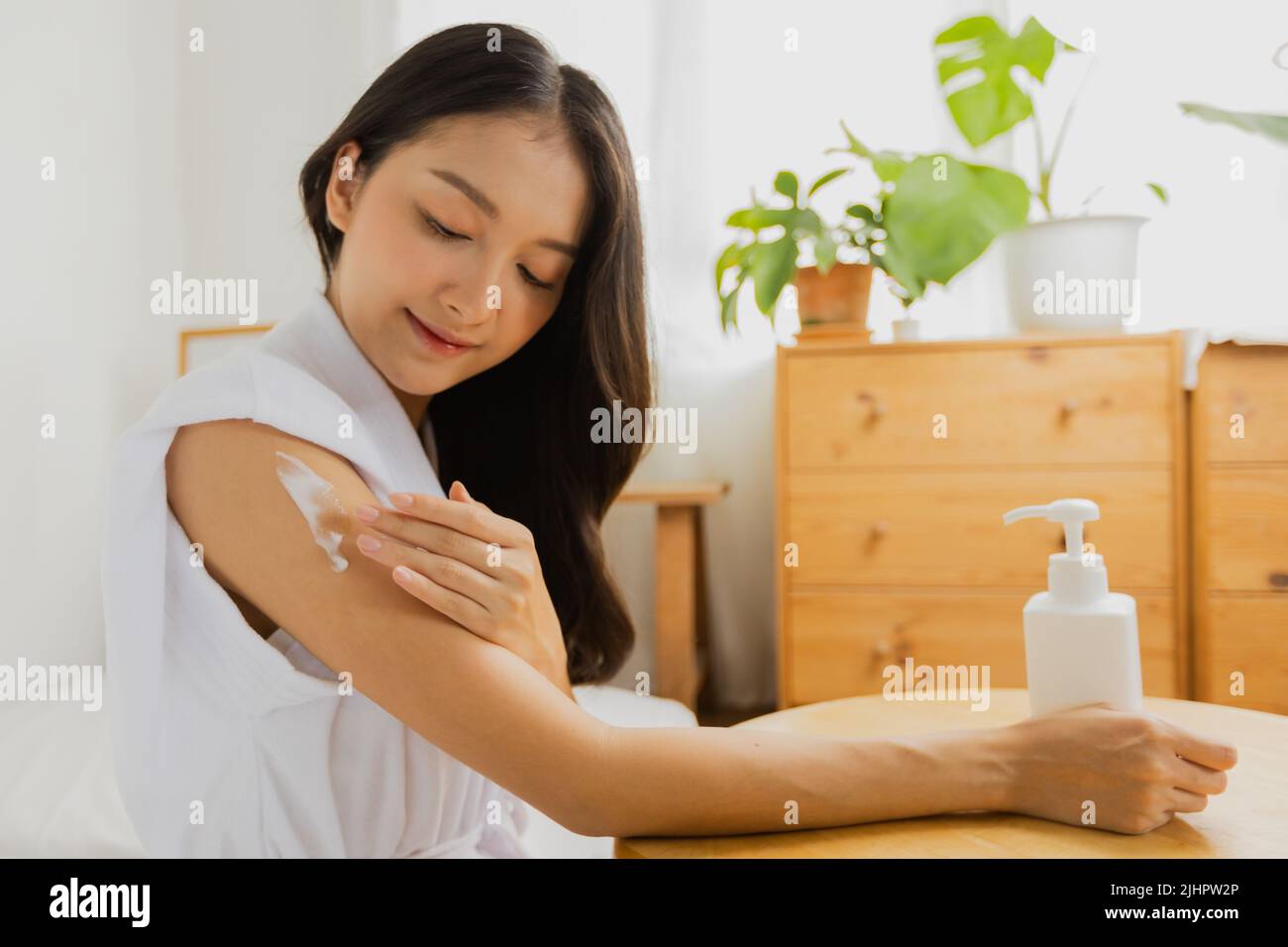 Beautiful Asian woman press bottle of skin lotion cream to apply moisturizing on her hand, treatment and body care Stock Photo