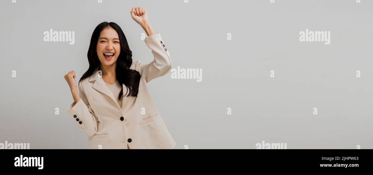 Successful and attractive Asian businesswoman show hand up to celebrate, success and glad woman in white suit isolated in studio Stock Photo