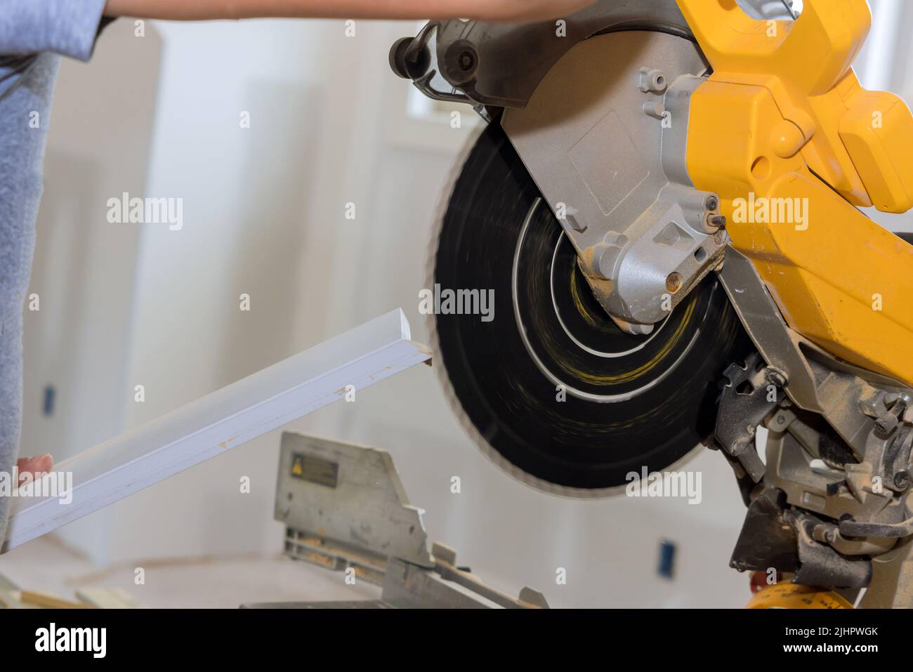 On the miter saw, a construction worker cuts wood moldings and