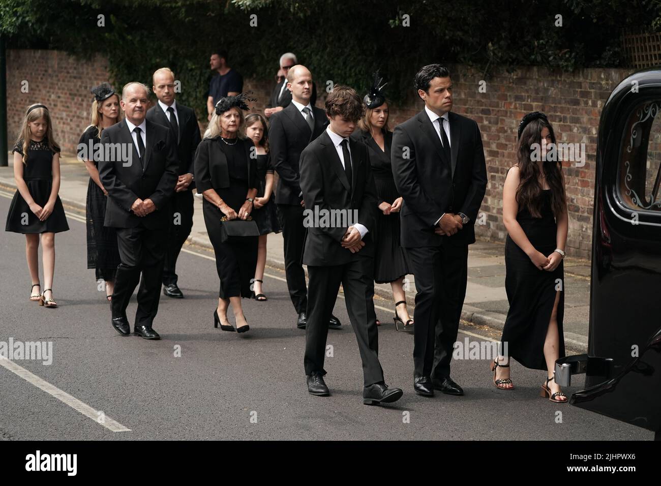 (left to right) Son Hugo, husband Sebastien Bowen, and daughter Eloise, walk with family behind the hearse as it arrives for the funeral service of Dame Deborah James at St Mary's Church in Barnes, west London. Picture date: Wednesday July 20, 2022. Stock Photo