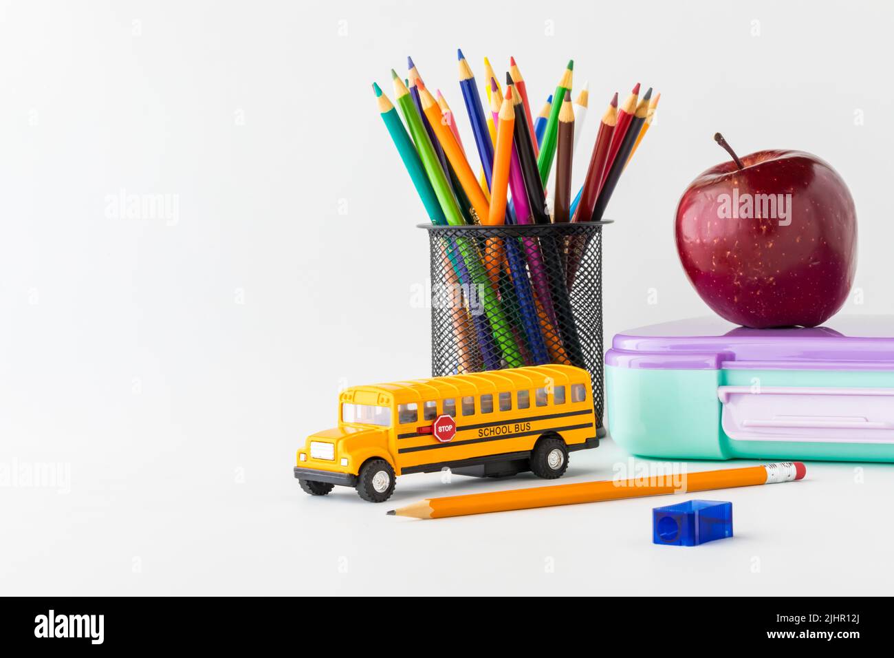 Back to school supplies including pencil crayons, lunchbox and apple. Stock Photo