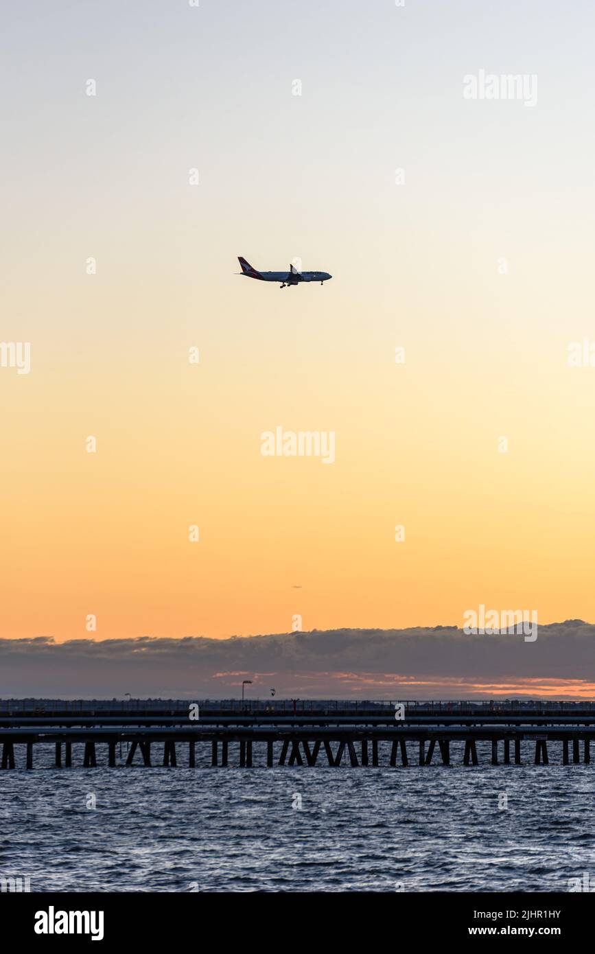 A Qantas plane on its approach to Sydney Airport above Botany Bay at sunset Stock Photo
