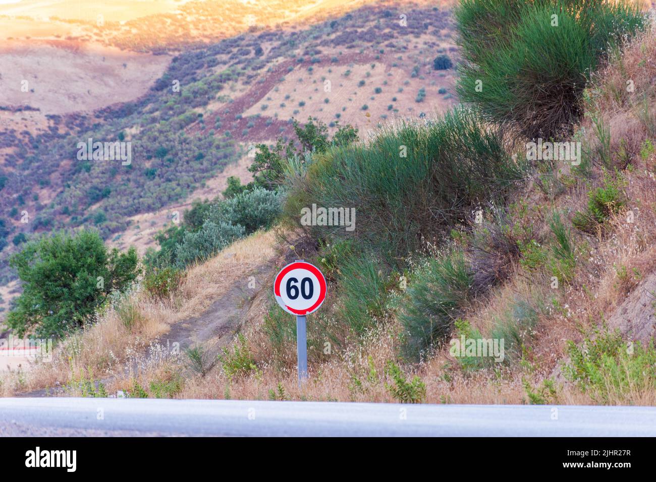 View of a traffic sign with a speed limit of 60 kilometers per hour on a countryside road. Stock Photo