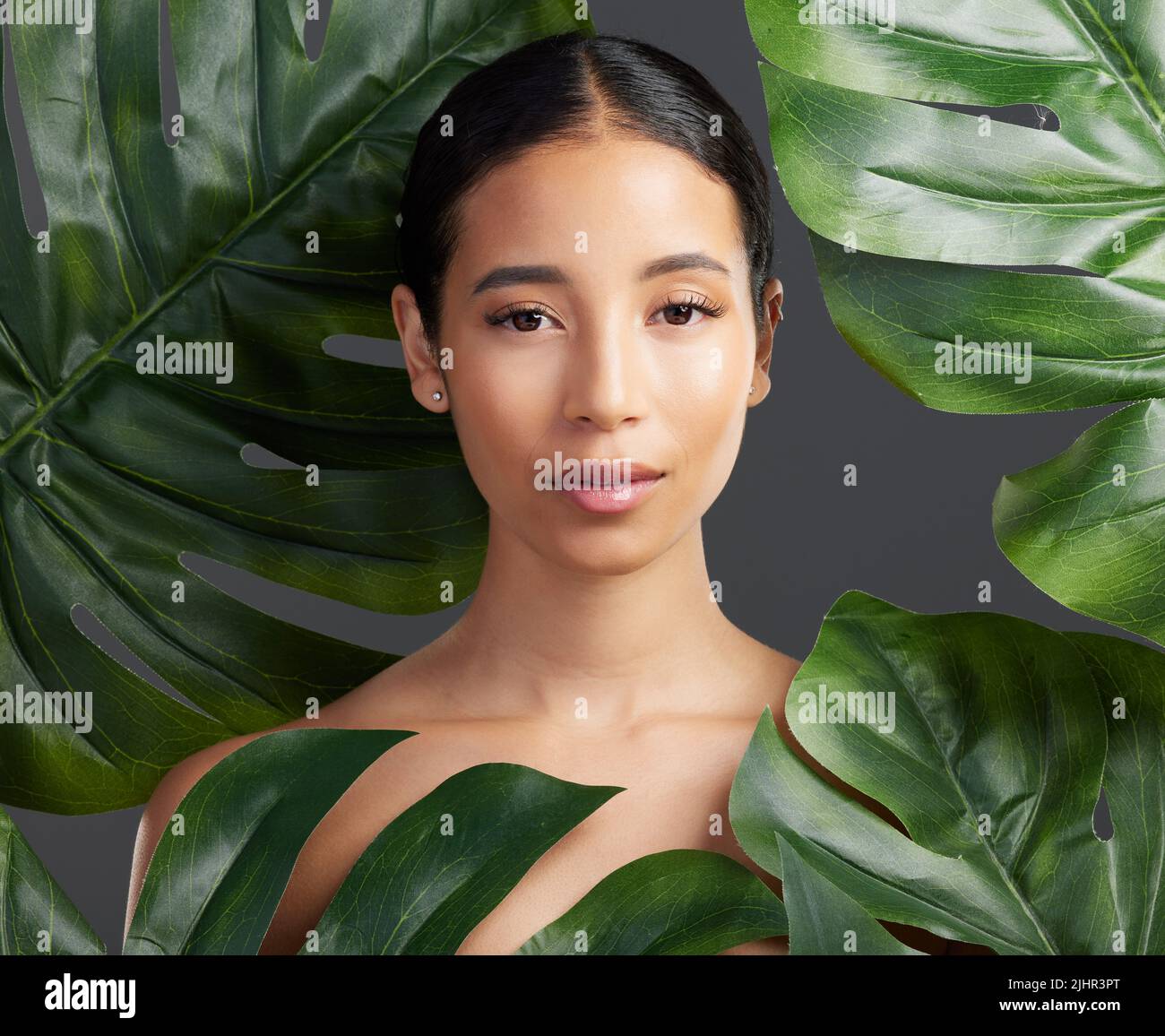 Studio portrait of a beautiful mixed race woman posing with a leaf ...