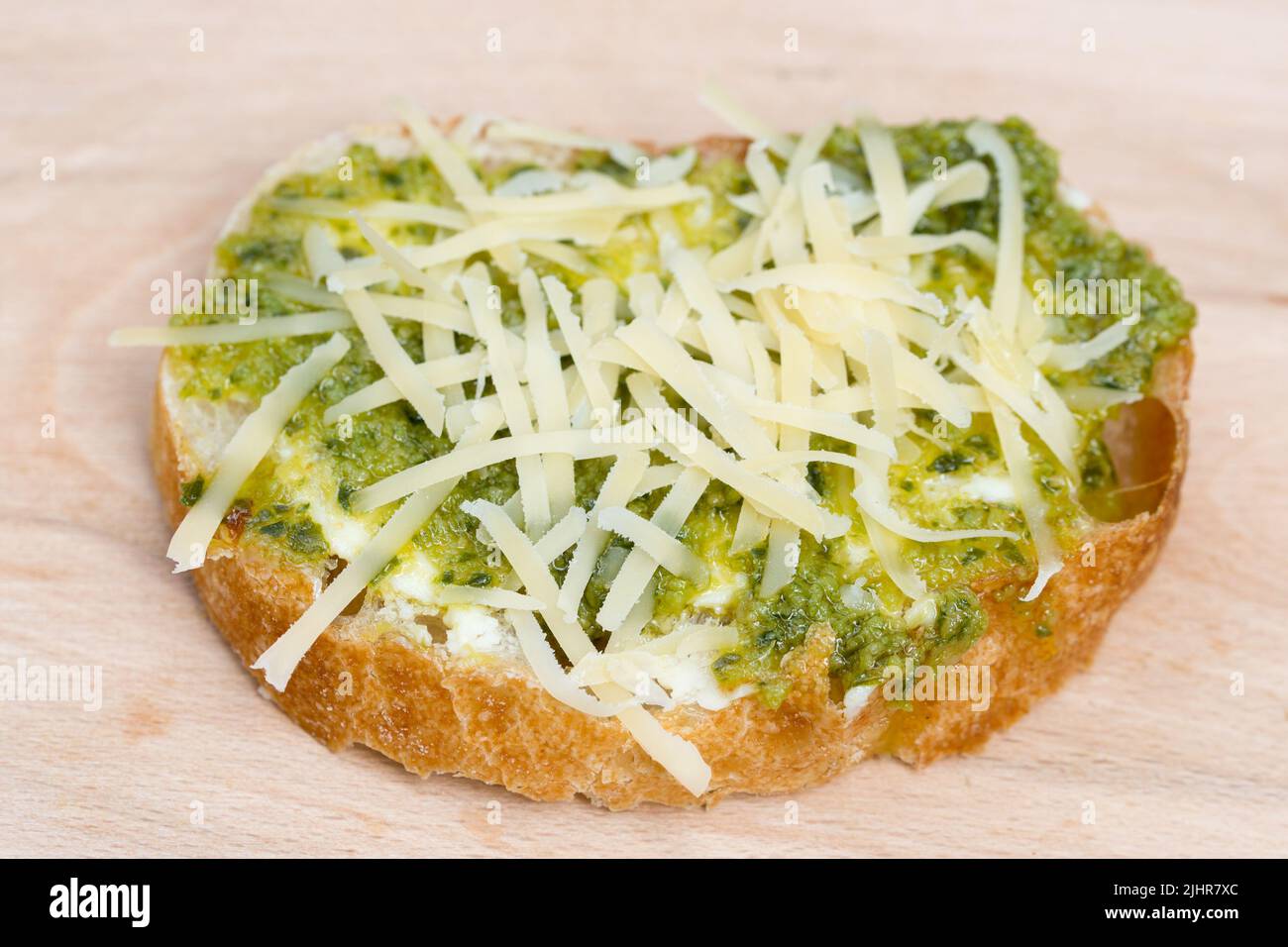 small open sandwich with vegetarian spread and grated cheese on wooden board selective focus Stock Photo
