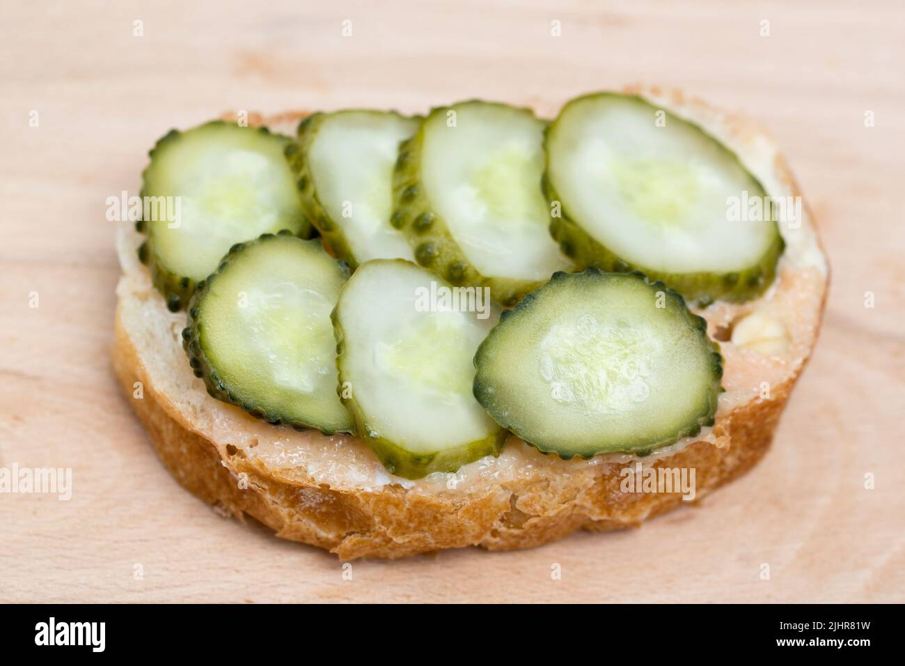 small open sandwich with spread and cucumber on wooden board Stock Photo