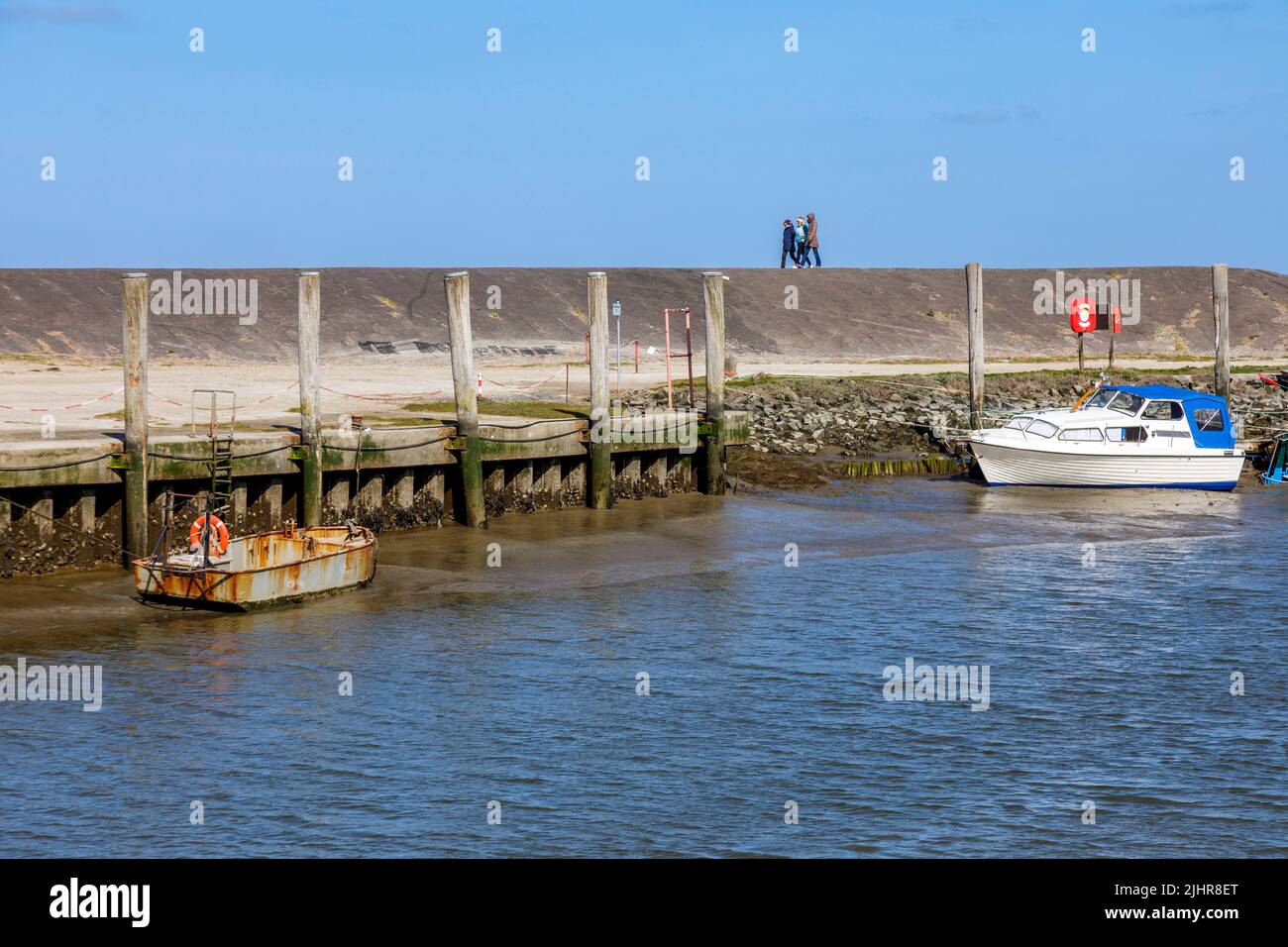 Everschopsiel Hafen in Nordfriesland bei ablaufendem Wasser, Urlauber auf dem Deich Stock Photo