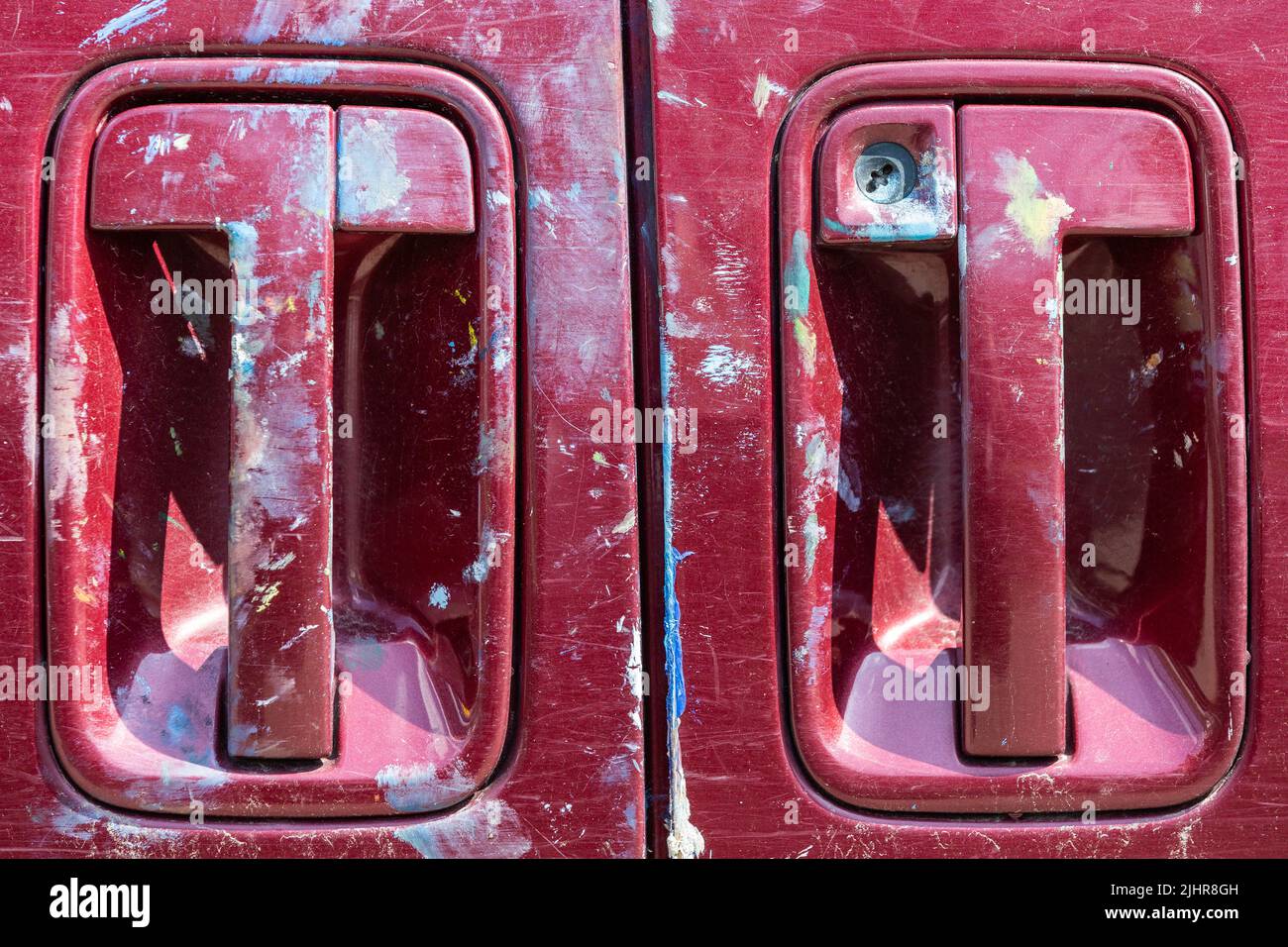 Two red car door handles, stained with white marks. Stock Photo