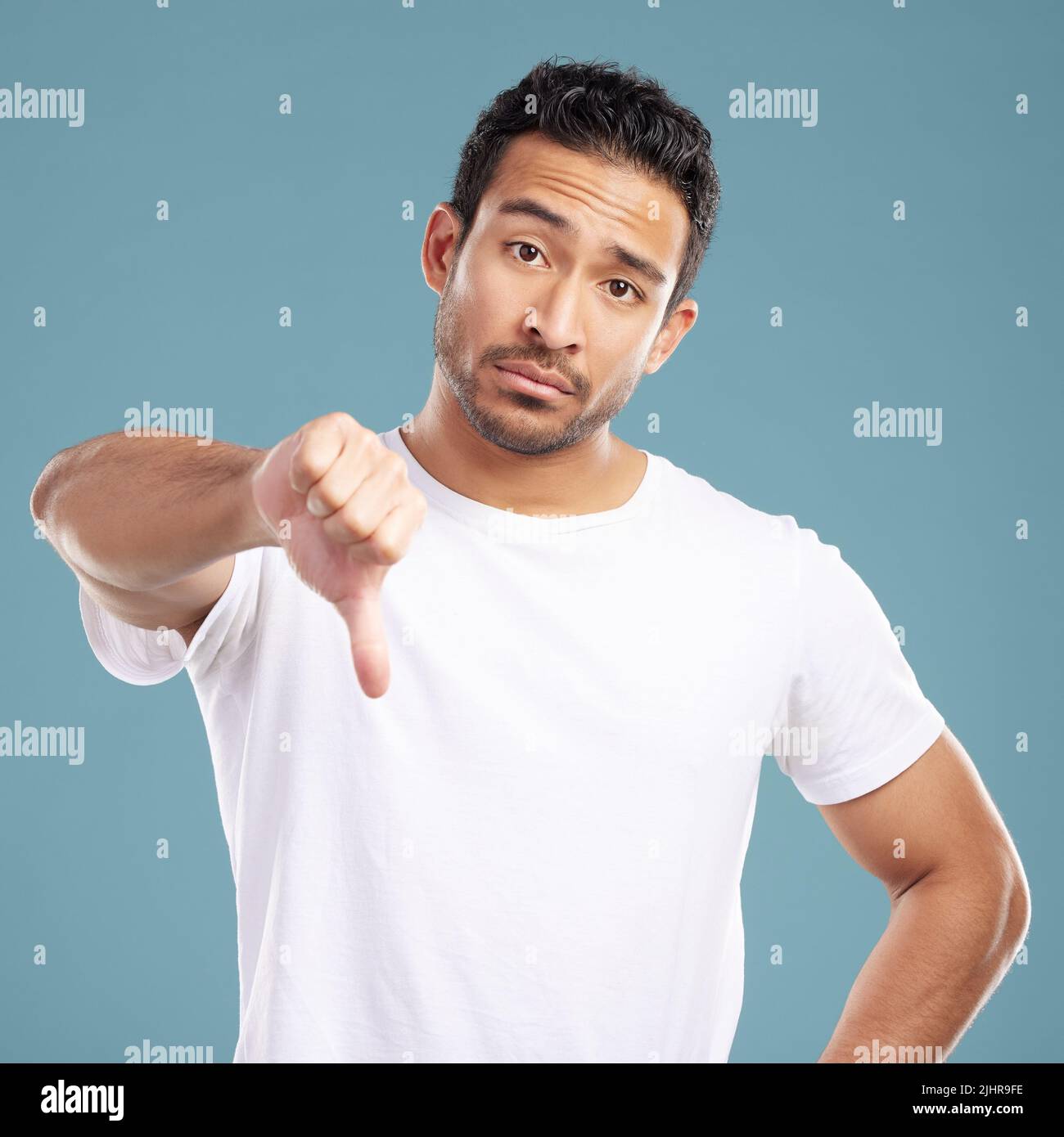 Handsome young guy showing double thumbs down Stock Photo - Alamy