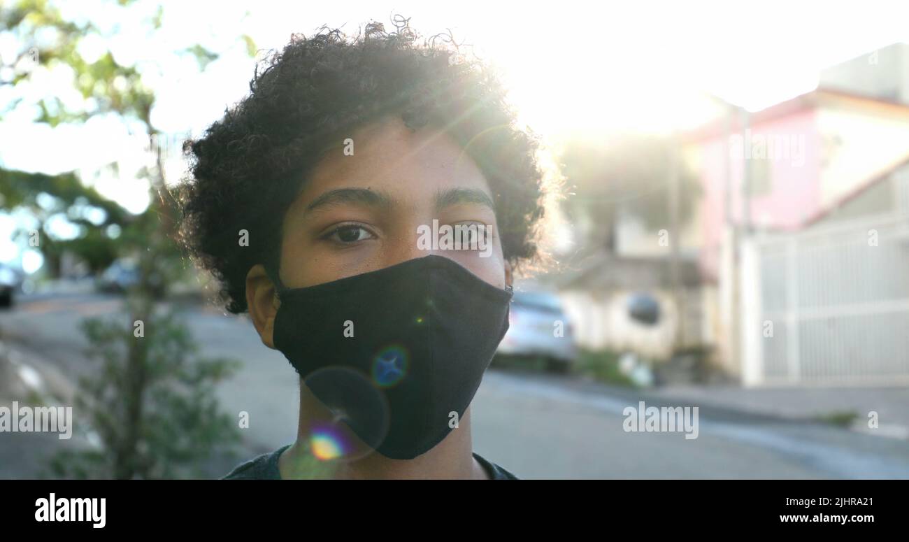 Mixed race young boy wearing covid19 face mask in urban street Stock