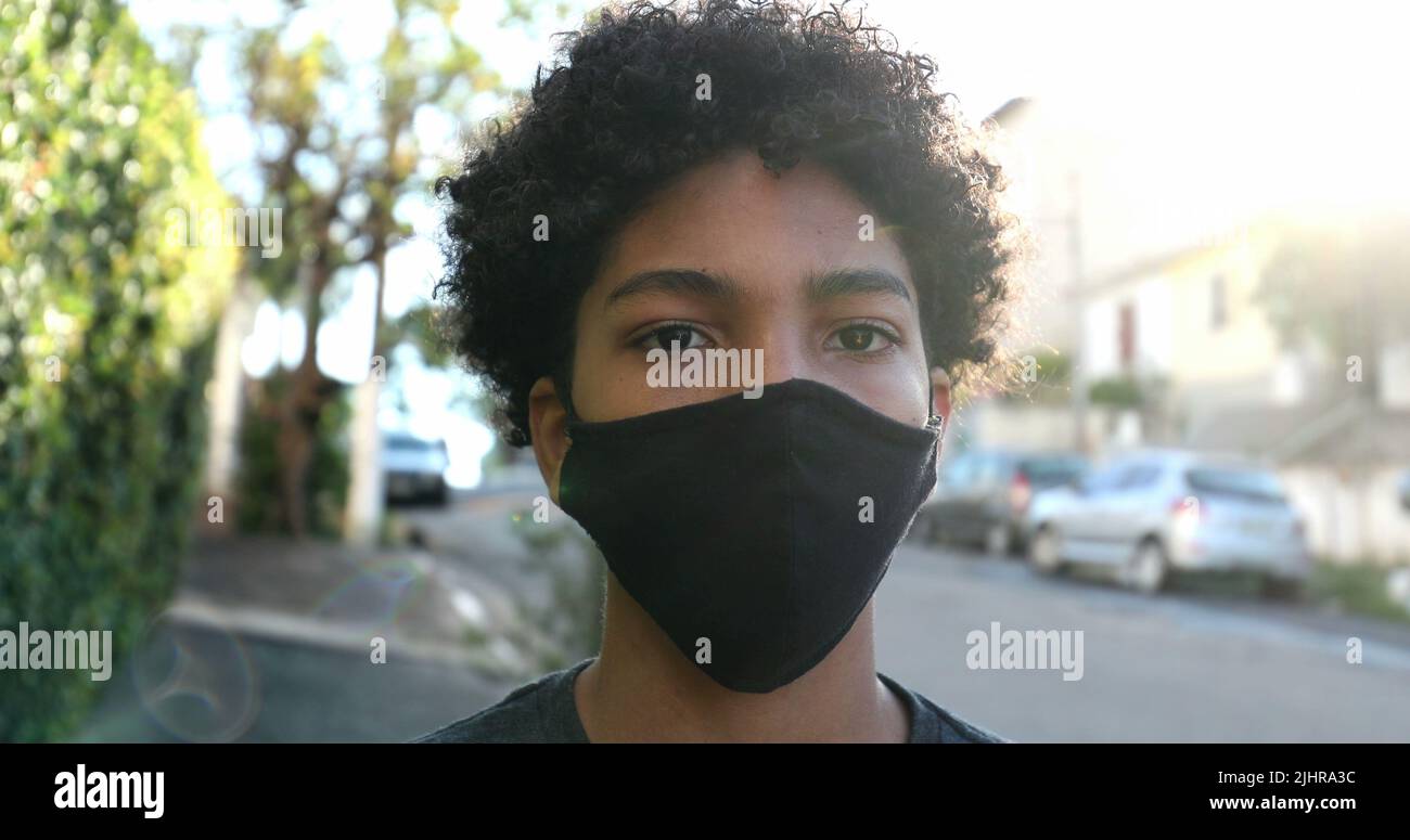 Mixed race young boy wearing covid19 face mask in urban street Stock