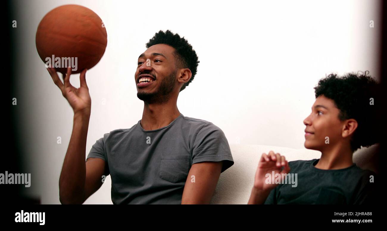 Older brother teaching younger sibling to spin basketball with finger