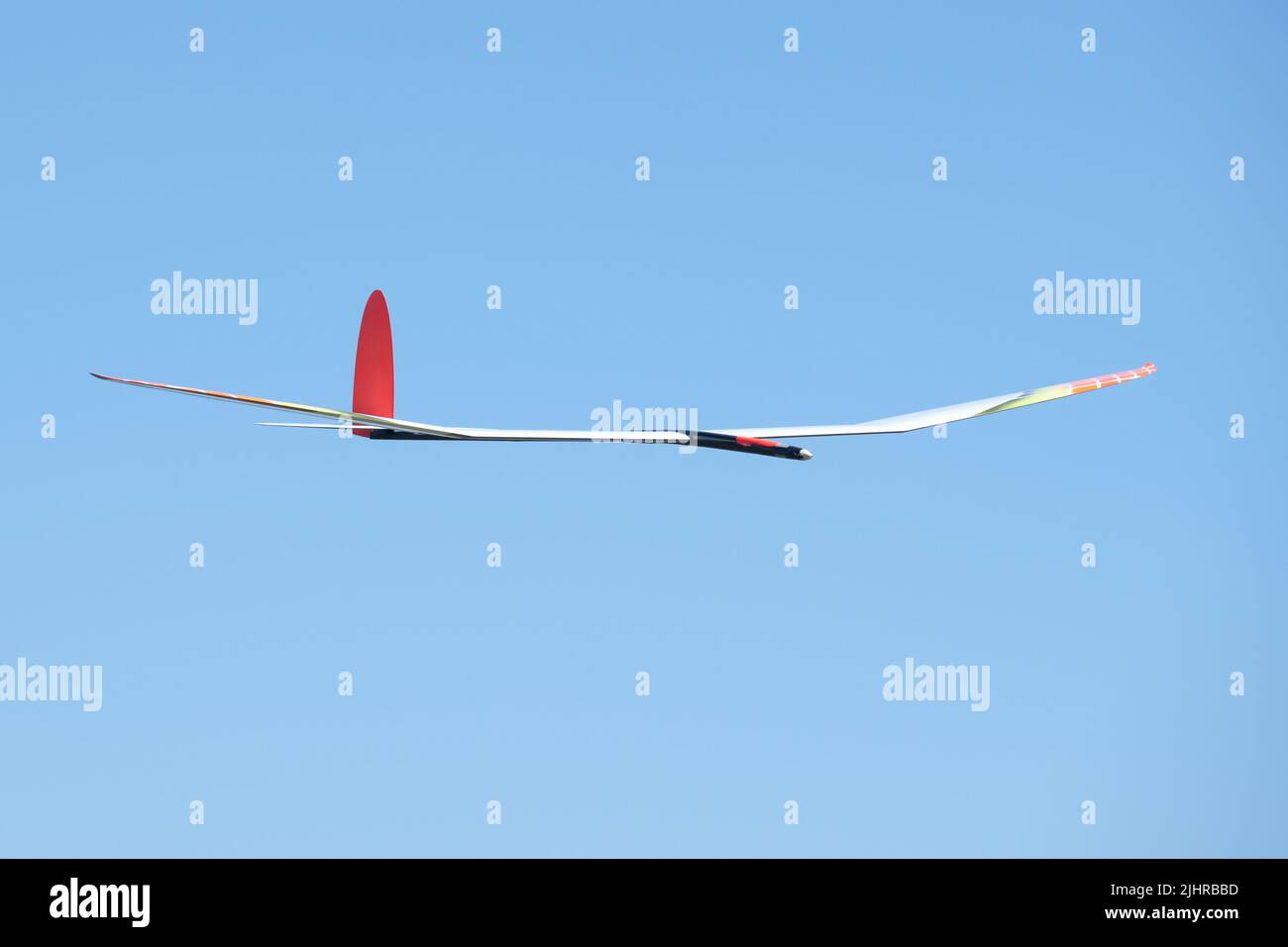 A high performance remote-controlled glider of the F5J competition class with an electric motor  flying in the blue summer sky. Seen in Germany in Jul Stock Photo
