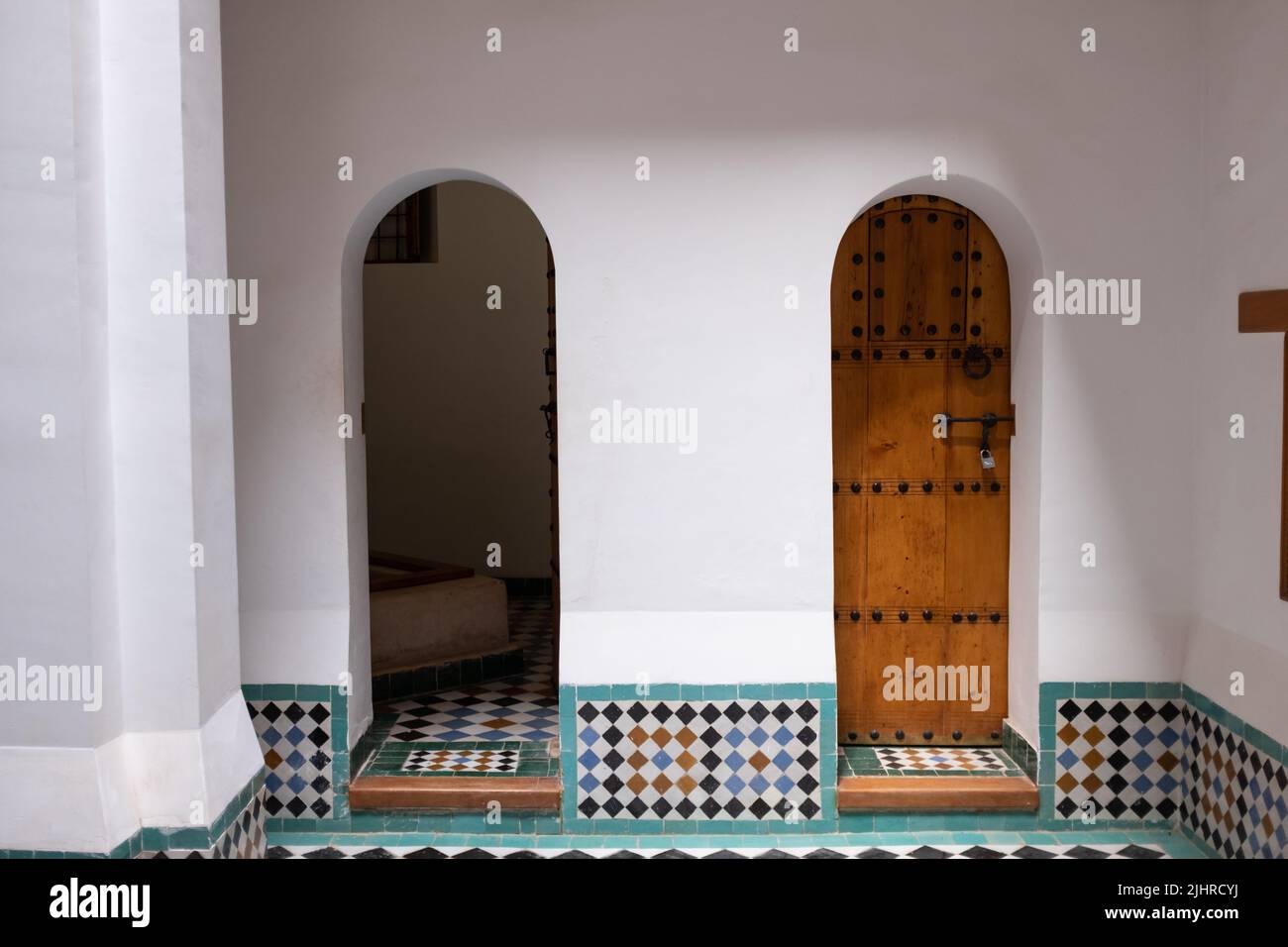 Two tiny wooden doors, one closed the other open on an Arabian style with white walls room in Marrakesh, Morocco Stock Photo