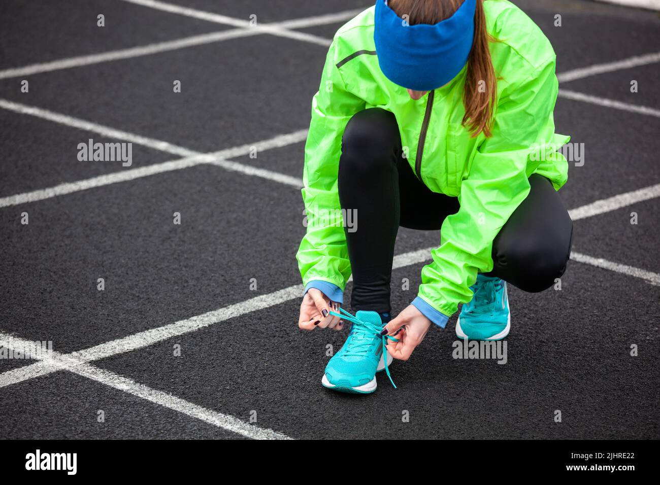 Cropped shot of a woman tying her shoelaces before running on a stadium. Stock Photo